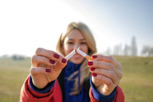 A woman snaps a cigarette in two.
