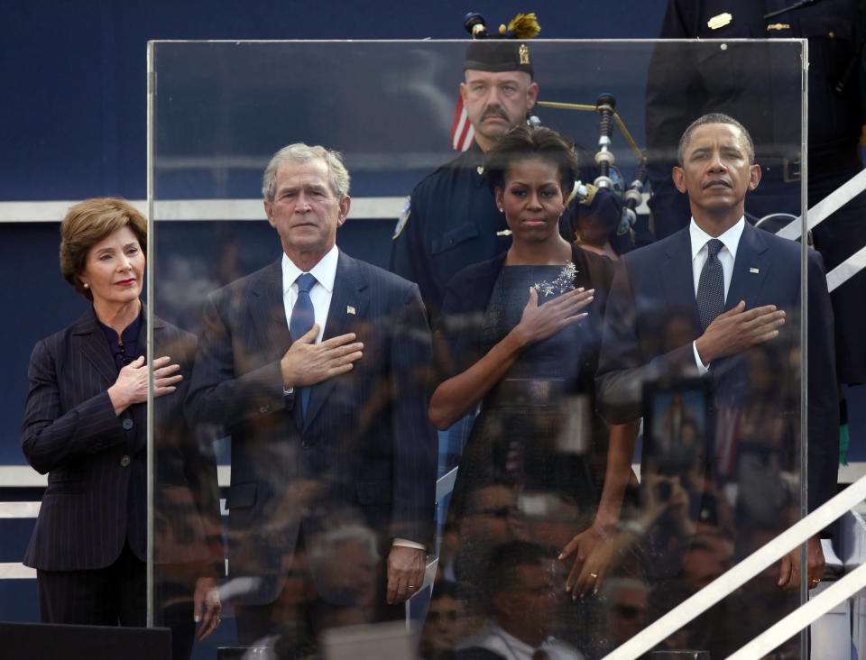 Former first lady Laura Bush, from left, former President George W. Bush, first lady Michelle Obama and President Barack Obama hold hands to their hearts during the national anthem as friends and relatives of the victims of 9/11 gather for a ceremony marking the 10th anniversary of the attacks at the National September 11 Memorial at the World Trade Center site, Sunday, Sept. 11, 2011, in New York. (AP Photo/Jason DeCrow)