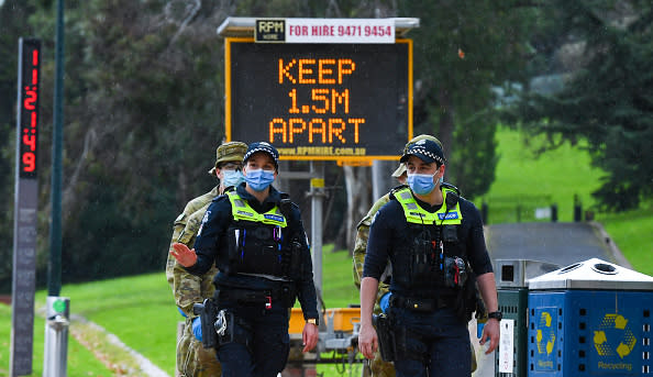 Police officers and soldiers patrol a popular running track in Melbourne.