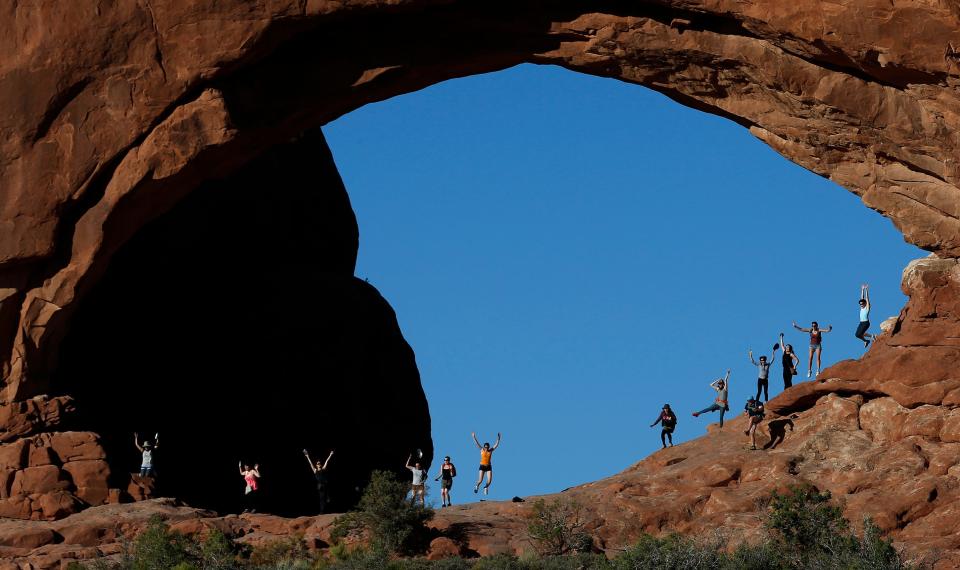 A group of visitors try to jump in unison at North Window in Arches National Park on June 21, 2013.
