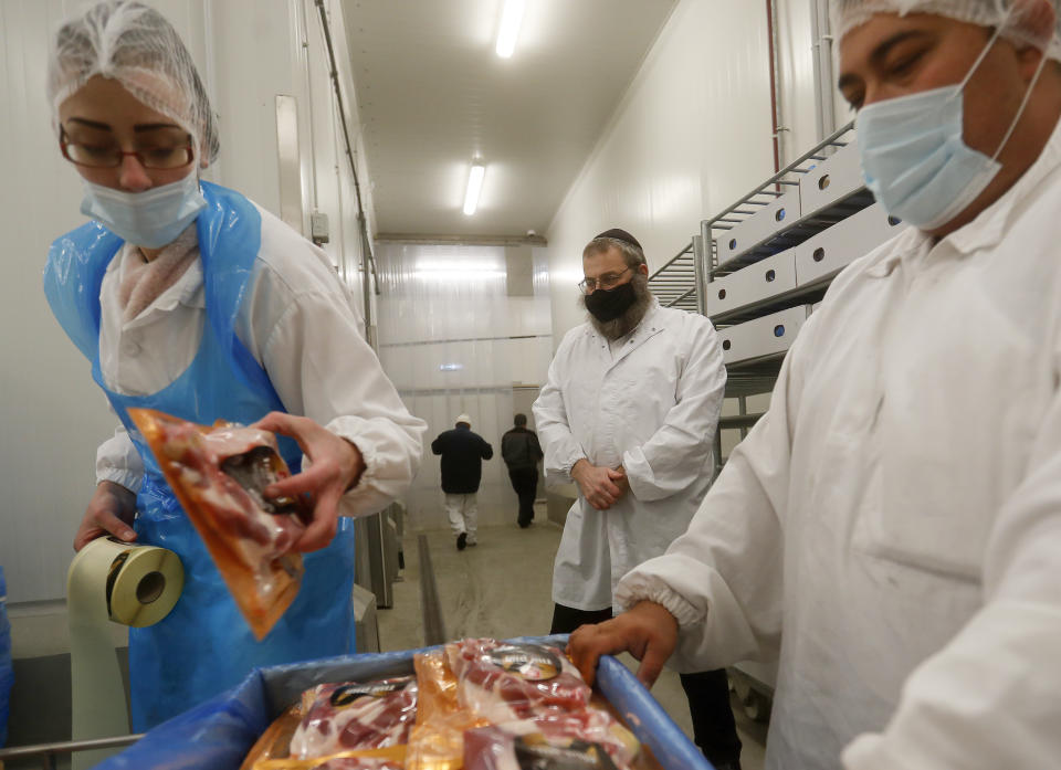 An Orthodox rabbi, centre, looks at workers packing Kosher poultry meat in a Kosher slaughterhouse in Csengele, Hungary on Jan. 15, 2021. Hungarian Jewish community, exporter of Kosher meat, fear that the European Court of Justice verdict on upholding a Belgian law that banned ritual slaughter could have an affect on other EU member states' regulation on Kosher slaughter. Animal rights groups that pushed for the Flanders law argue that ritual slaughter without stunning amounts to animal cruelty. (AP Photo/Laszlo Balogh)