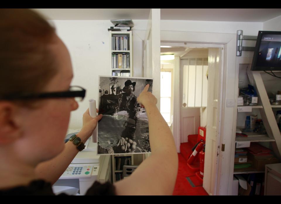 A Handel House Museum worker holds a photograph of Hendrix, showing the exact location of what used to be the star's bedroom, when he was living in the house during the late 1960s.     AP Photo/Lefteris Pitarakis