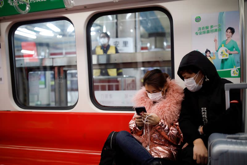 FILE PHOTO: People wearing masks travel in the subway, as the country is hit by an outbreak of the new coronavirus, in Beijing