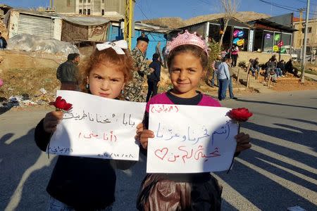 Girls carry banners as they wait at the Masnaa border crossing between Lebanon and Syria, for the arrival of their relatives, who are rebel fighters who left the town of Zabadani, December 28, 2015. REUTERS/Hassan Abdallah