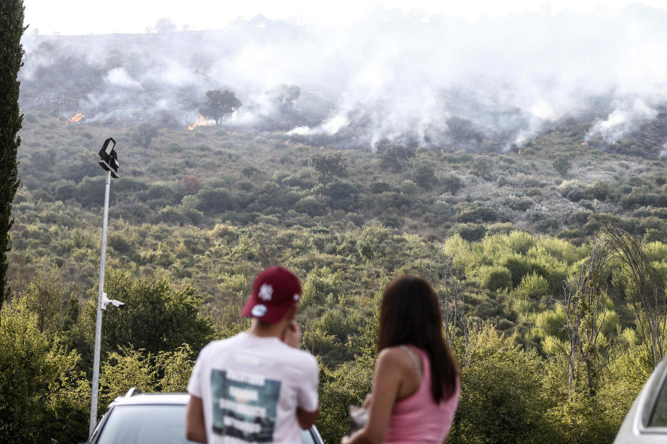 People watch as a fire burns on Castillo mountain park near Tivoli a few miles from Rome, Italy, Friday, Aug. 13, 2021. Intense heat baking Italy pushed northward towards the popular tourist destination of Florence Friday while wildfires charred the country's south, and Spain appeared headed for an all-time record high temperature as a heat wave kept southern Europe in a fiery hold. (Cecilia Fabiano/LaPresse via AP)