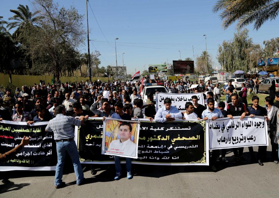 Mourners chant slogans during a symbolic funeral for the bureau chief of a local radio station in Baghdad, Iraq, Sunday, March 23, 2014. An junior officer working for Iraqi President Jalal Talabani, also an ethnic Kurd, shot dead Mohammed Bdaiwi, in the posters, a well-known radio journalist during a quarrel Saturday near the leader's east Baghdad residence, police said. (AP Photo/Karim Kadim)