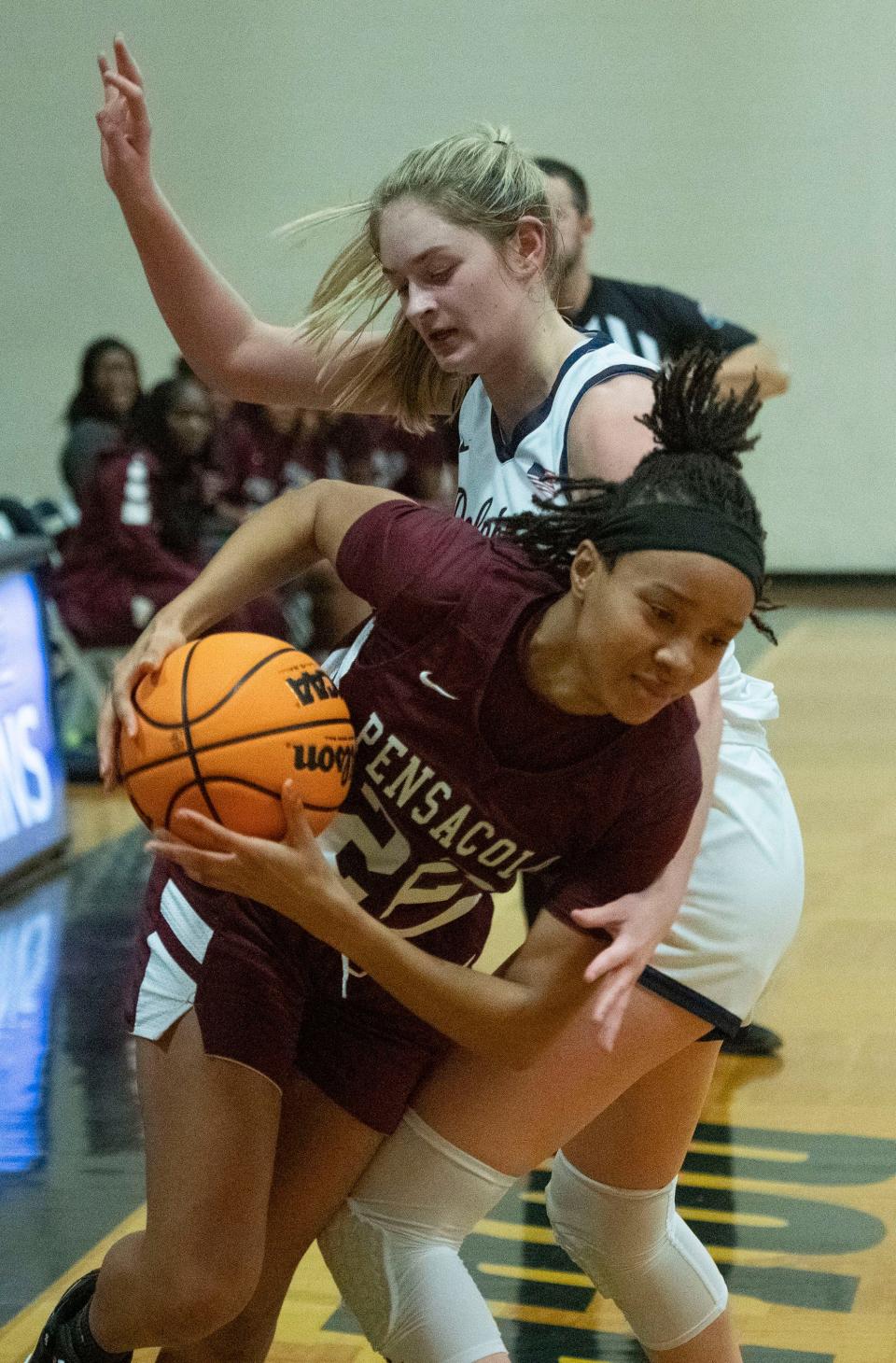 Pensacola High Schools Jordan Latham (No. 22) moves past Gulf Breeze High School's Piper Tieman (No. 5) as she drives into the paint on Friday, Jan. 5, 2024.