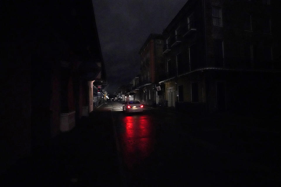 A passing car's headlights illuminate a darkened Bourbon Street in the French Quarter of New Orleans, Wednesday, Oct. 28, 2020. Hurricane Zeta passed through Wednesday leaving much of the city and metro area without power. (AP Photo/Gerald Herbert)