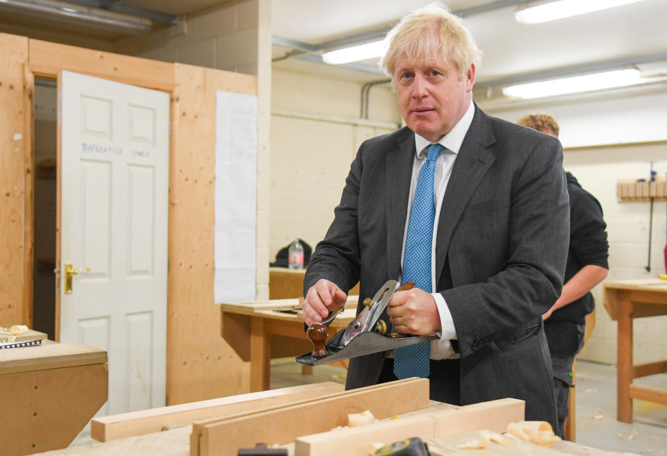 Britain's Prime Minister Boris Johnson uses a plane as he talks with carpentry students in a wood working class aduring his visit to Exeter College in Exeter, southwest England on September 29, 2020. - British Prime Minister Boris Johnson revealed Tuesday he was obese when he contracted the novel coronavirus COVID-19 earlier this year, but after losing weight said he now felt much better. "I am fitter than I was before, it may irritate you to know," he said, when asked by a reporter about his health following a speech on education. (Photo by Finnbarr Webster / POOL / AFP) (Photo by FINNBARR WEBSTER/POOL/AFP via Getty Images)