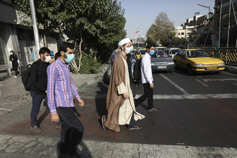 A cleric and his friends wearing protective face masks to help prevent the spread of the coronavirus cross an intersection in downtown Tehran, Iran, Sunday, Sept. 20, 2020. Iran's president dismissed U.S. efforts to restore all U.N. sanctions on the country as mounting economic pressure from Washington pushed the local currency down to its lowest level ever on Sunday. (AP Photo/Vahid Salemi)