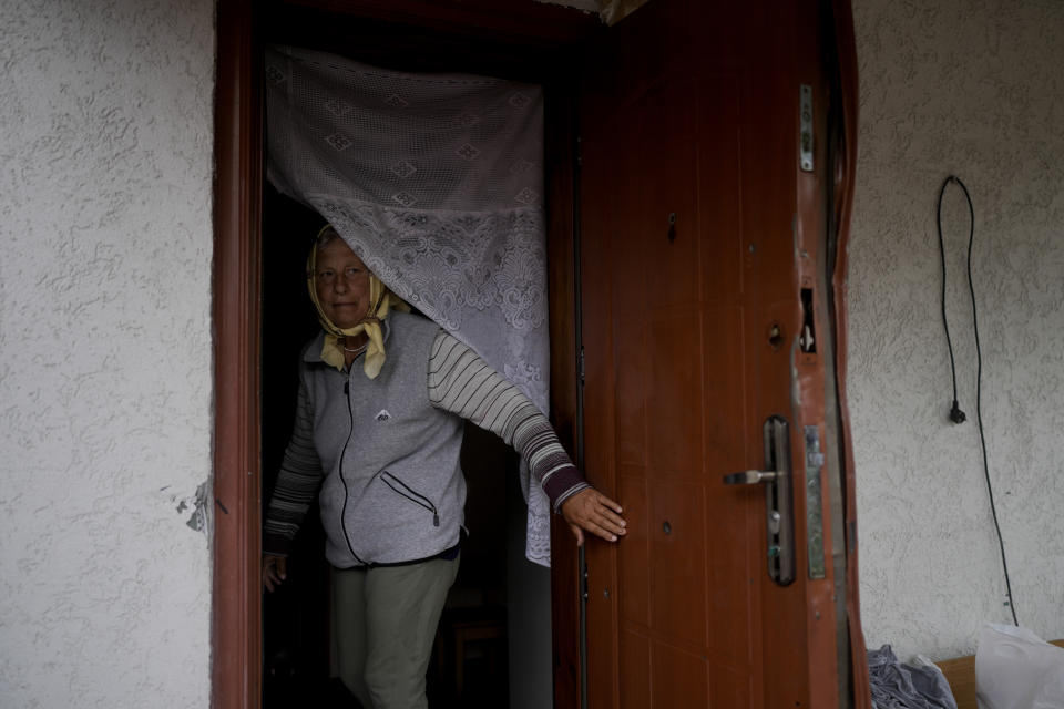 Tetiana Kutsenko stands at the entrance of her home that was occupied by Russian soldiers in Makariv, on the outskirts of Kyiv, Ukraine, Tuesday, June 14, 2022. When Kutsenko got back her home that Russian troops had occupied, she found bloodstains and an apparent bullet hole on the bathroom floor and tripwires in her back yard. (AP Photo/Natacha Pisarenko)