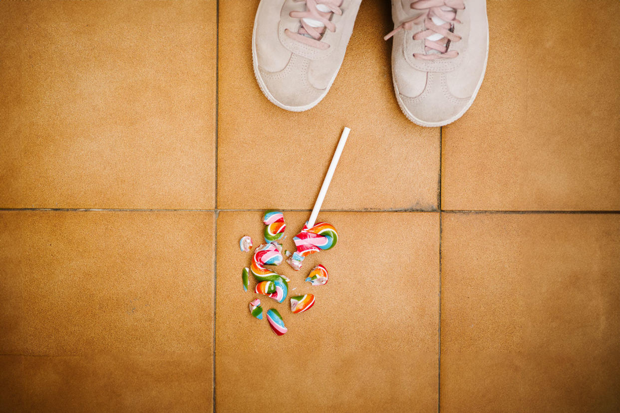 A child looks down at her broken lollipop on the floor Getty Images/Israel Sebastian