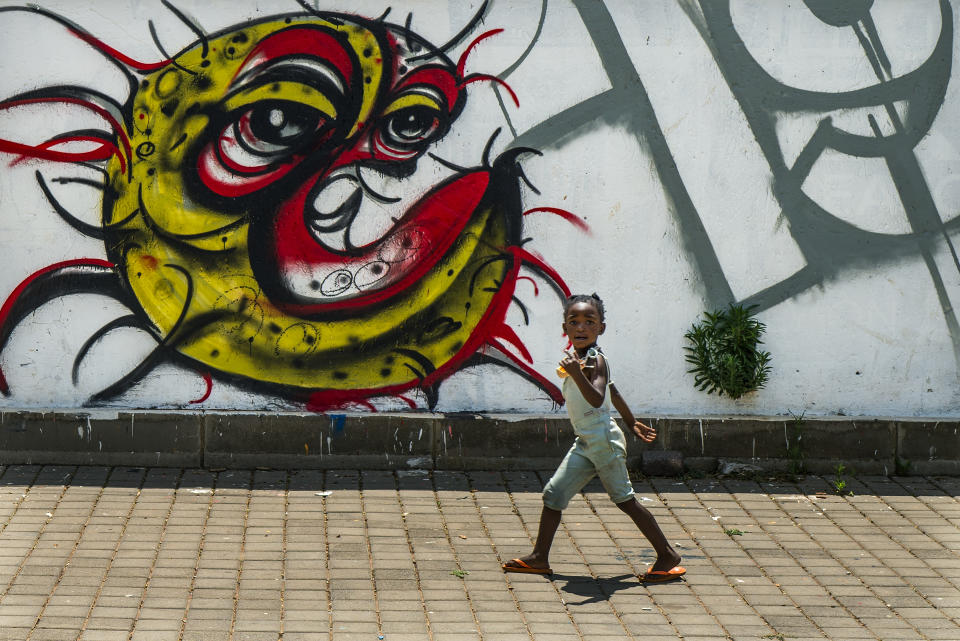 A child walks past a COVID-19 graffiti in Soweto's Orlando West township near Johannesburg, South Africa, Thursday Nov. 19, 2020. Africa has surpassed 2 million confirmed coronavirus cases as the continent's top public health official warns that “we are inevitably edging toward a second wave” of infections. The 54-nation continent of 1.3 billion people is being warned against “prevention fatigue” as countries loosen pandemic restrictions to ease their economies’ suffering and more people travel. (AP Photo/Jerome Delay)