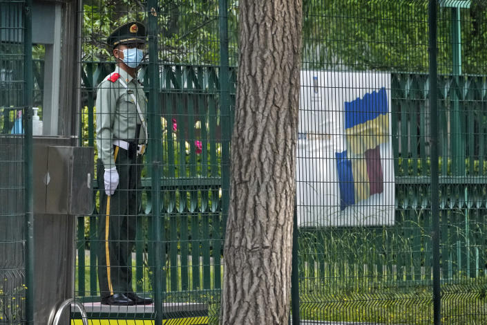 A paramilitary policeman stands guard near a billboard showing a support for Ukraine on display in between fences at the Romania Embassy in Beijing, Thursday, May 17, 2023. Embassies in Beijing have been asked by the Chinese government to avoid displaying propaganda after some raised Ukrainian flags or set up placards declaring support for Ukraine. (AP Photo/Andy Wong)