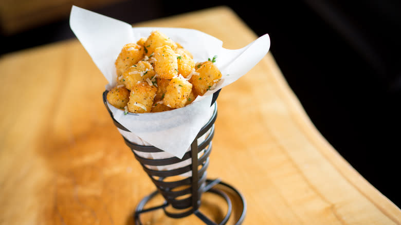 Seasoned tater tots in a paper-lined restaurant cone