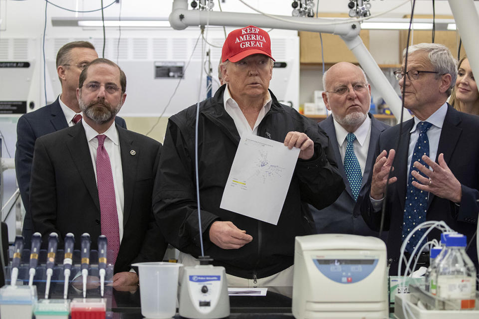 President Donald Trump holds up a picture as he listens during a meeting with Health and Human Services Secretary Alex Azar, left, Associate Director for Laboratory Science and Safety Steve Monroe, and Centers for Disease Control and Prevention Director Dr. Robert Redfield, about the coronavirus at the Centers for Disease Control and Prevention, Friday, March 6, 2020 in Atlanta. (AP Photo/Alex Brandon)
