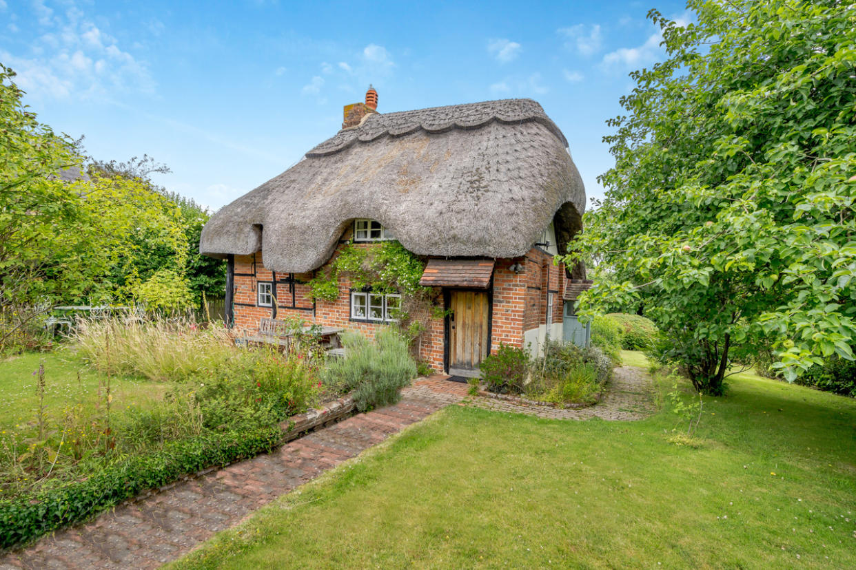 This cute cottage features a thatched roof, timber beams, and an inglenook fireplace. Photo: Strutt & Parker