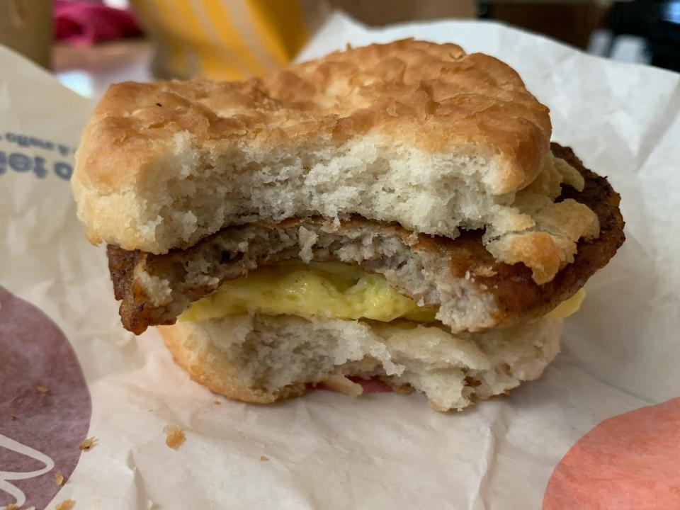 McDonald's sausage, egg, and cheese biscuit with bite taken out of it on white wrapper