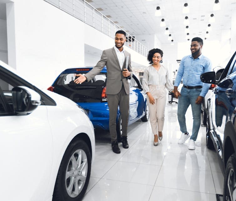 Dealership salesman showing a car to a couple