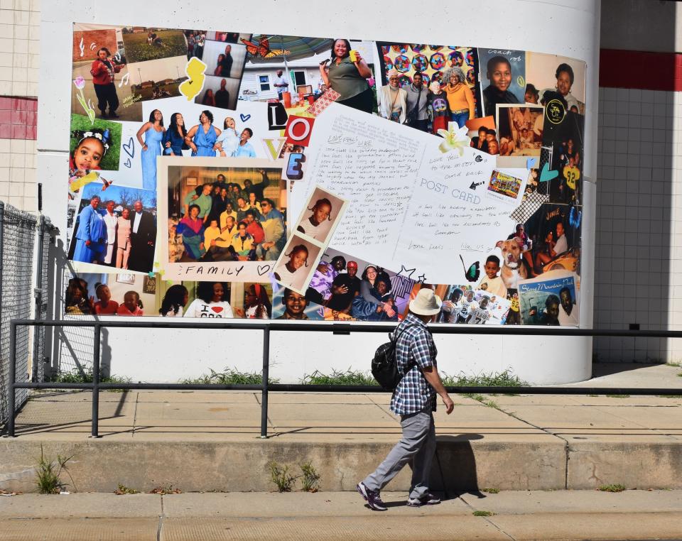A man looks at a recently installed collage while walking along rail tracks at the Rand Transportation Center in Camden.