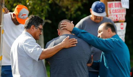 Neighbours comfort Jose Gonzales (centre), who was prevented from returning to his wife and his home at the scene of the investigation around the area of the SUV vehicle where two suspects were shot by police following a mass shooting in San Bernardino, California December 3, 2015. REUTERS/Mike Blake/File Photo