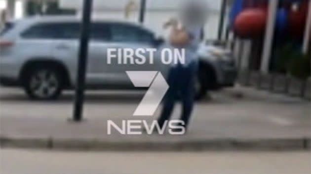 Courtney Topic standing outside the Hungry Jack's, a playground in the background, with the large knife in her hand. Photo: 7News