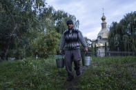 Andriy Kotsar, who was tortured by Russian soldiers, carries buckets with water near Pishchanskyi monastery in the recently liberated town of Izium, Ukraine, Tuesday, Sept. 20, 2022. Russian torture in Izium was arbitrary, widespread and absolutely routine, extending to both civilians and soldiers throughout the city, an AP investigation has found. (AP Photo/Evgeniy Maloletka)