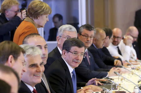 Turkish Prime Minister Ahmet Davutoglu (C) attends a lunch meeting with European Union leaders including Germany's Chancellor Angela Merkel (Back L) during an EU-Turkey summit in Brussels, as the bloc is looking to Ankara to help it curb the influx of refugees and migrants flowing into Europe, March 7, 2016. REUTERS/Olivier Hoslet/Pool