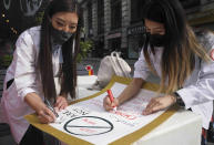 Dr. Michelle Lee, left, a radiology resident, and Ida Chen, right, a physician assistant student, prepare posters they carry at rallies protesting anti-Asian hate, Saturday April 24, 2021, in New York's Chinatown. Lee, who is Korean-born, and Chen, who is American-born Chinese, join medical professionals of Asian and Pacific Island descent who feel the anguish of being racially targeted because of the virus while toiling to keep people from dying of it. (AP Photo/Bebeto Matthews)