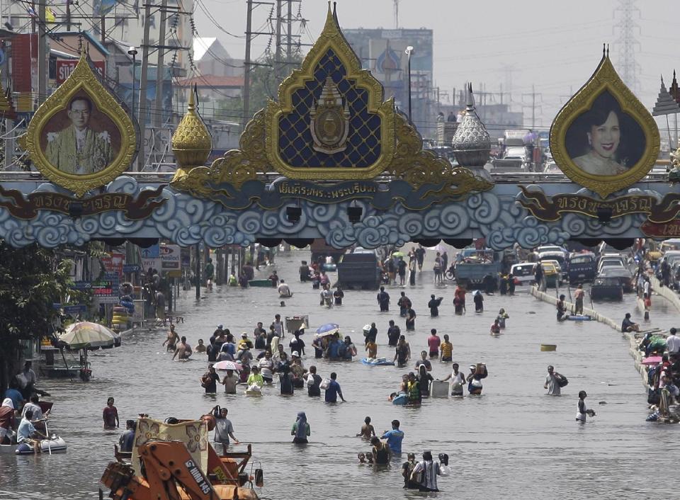 FILE - In this Oct. 21, 2011 file photo, resident wade through floods in Rangsit district on the outskirts of Bangkok, Thailand. A United Nations panel of scientists has drafted a list of eight ``key risks” about climate change that’s easy to understand and illustrates the issues that have the greatest potential to cause harm to the planet. The list is part of a massive report on how global warming is affecting humans and the planet and how the future will be worse unless something is done about it. The report is being finalized at a meeting on the weekend of March 29, 2014 by the Intergovernmental Panel on Climate Change. (AP Photo/Aaron Favila, File)