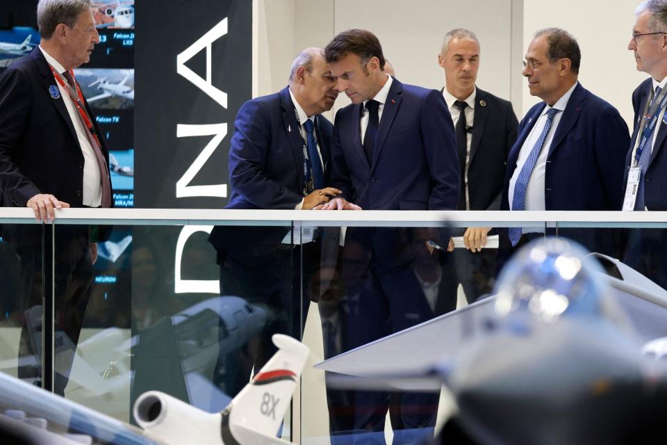 French President Emmanuel Macron speaks with Dassault Aviation CEO Eric Trappier (left), in front of a model of the Dassault Rafale, as he visits the International Paris Air Show in June 2023. <em>Photo by LUDOVIC MARIN/POOL/AFP via Getty Images</em>