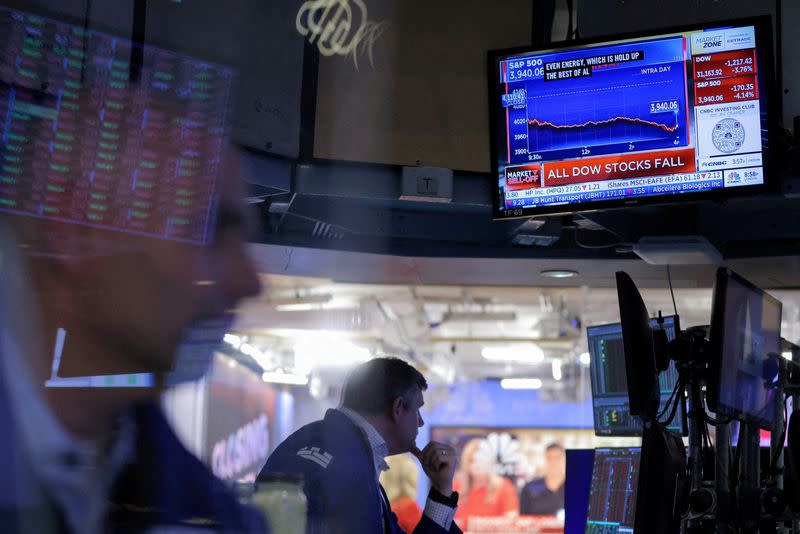 FILE PHOTO: A screen displays market news as traders work on the trading floor at the New York Stock Exchange (NYSE) in Manhattan, New York City
