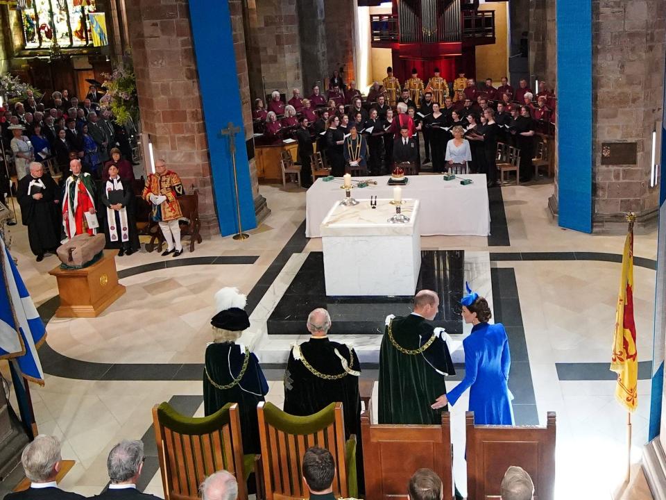 William, Kate, and others in large stone building and kate's hand on william's side