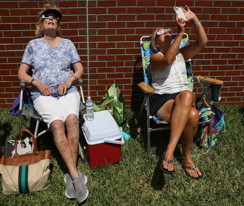 Mary Carroll-Mirylees (left) and Gail Mathes, both of Port St. Lucie, view the partial solar eclipse from Indian River State College on Monday, April 8, 2024, in Fort Pierce. The Hallstrom Planetarium projected a live feed of the solar eclipse from across the country, while crowds of people viewed the eclipse from the yard outside, using eclipse glasses and telescopes.