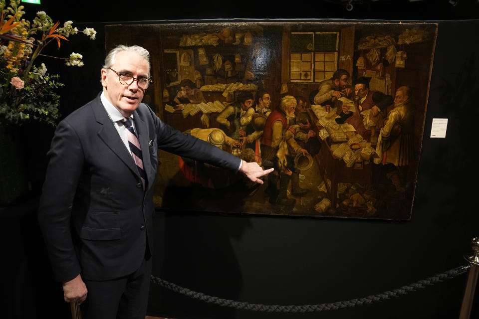 Art expert Stephane Pinta points to the painting "Payment of the Yearly Dues", also known as "The Peasants' Lawyer" by Pieter Brueghel The Young (estimated to be dating before 1618), Monday, March 27, 2023 at the Drouot auction house in Paris. A rare Brueghel the younger painting found behind a door in French home goes under the hammer in Paris at Drouot Auction house (AP Photo/Michel Euler)