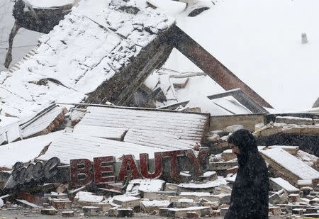 A man walks past the burned out remains of a business that was set on fire after the grand jury verdict in the Michael Brown shooting in Ferguson, Missouri, November 26, 2014. REUTERS/Jim Young