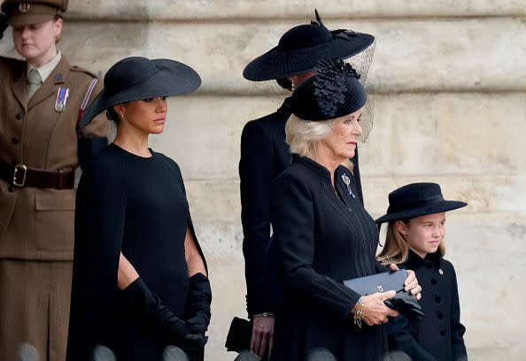LONDON, ENGLAND - SEPTEMBER 19: Meghan, Duchess of Sussex, Camilla, Queen Consort and Princess Charlotte of Wales watch as The Queen's funeral cortege borne on the State Gun Carriage of the Royal Navy as it departs Westminster Abbey on September 19, 2022 in London, England. Elizabeth Alexandra Mary Windsor was born in Bruton Street, Mayfair, London on 21 April 1926. She married Prince Philip in 1947 and ascended the throne of the United Kingdom and Commonwealth on 6 February 1952 after the death of her Father, King George VI. Queen Elizabeth II died at Balmoral Castle in Scotland on September 8, 2022, and is succeeded by her eldest son, King Charles III.  (Photo by Christopher Furlong/Getty Images)