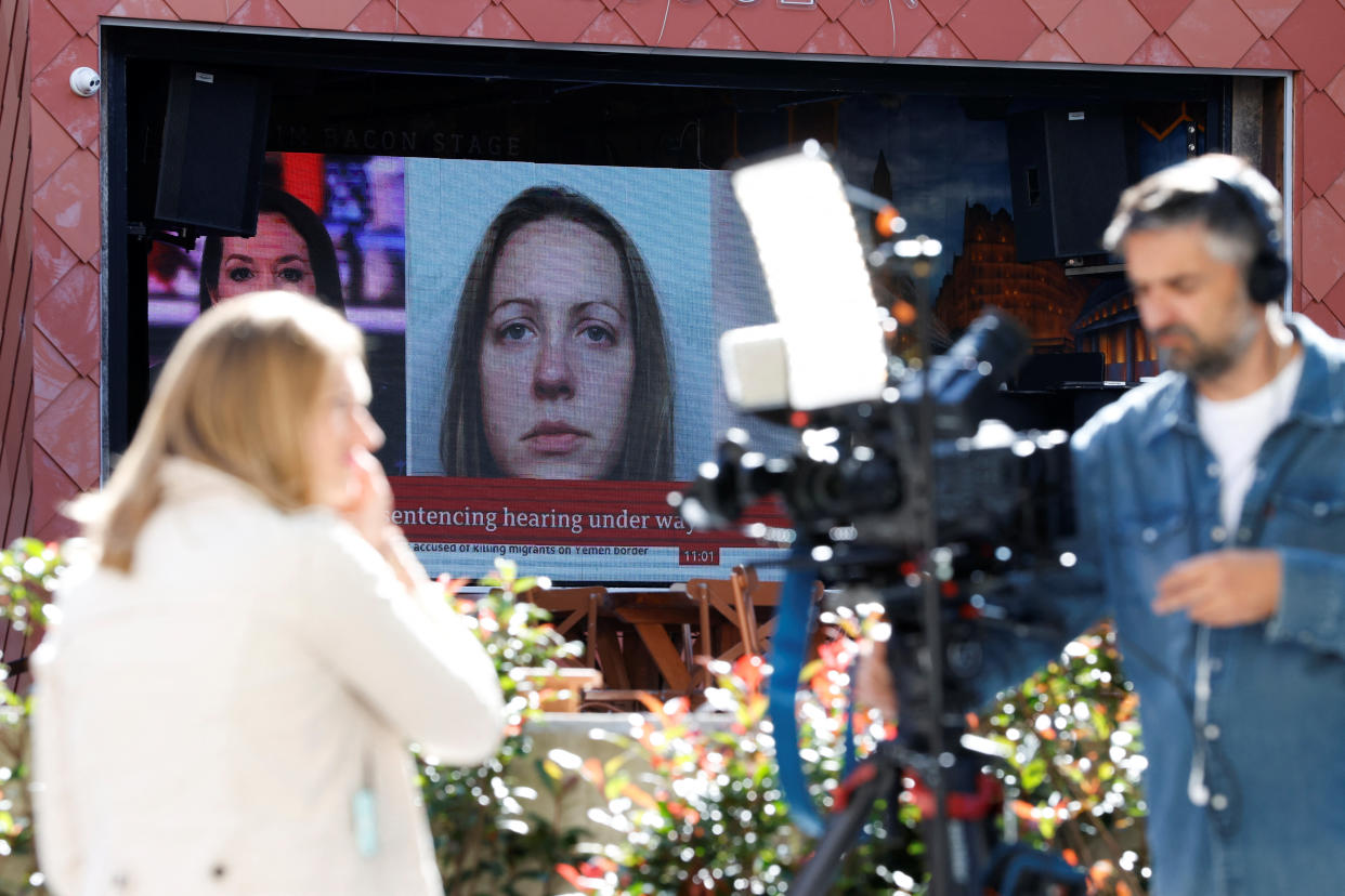 Members of the media work near a large screen showing a picture of convicted hospital nurse Lucy Letby, ahead of her sentencing, outside the Manchester Crown Court, in Manchester, Britain, August 21, 2023. REUTERS/Phil Noble