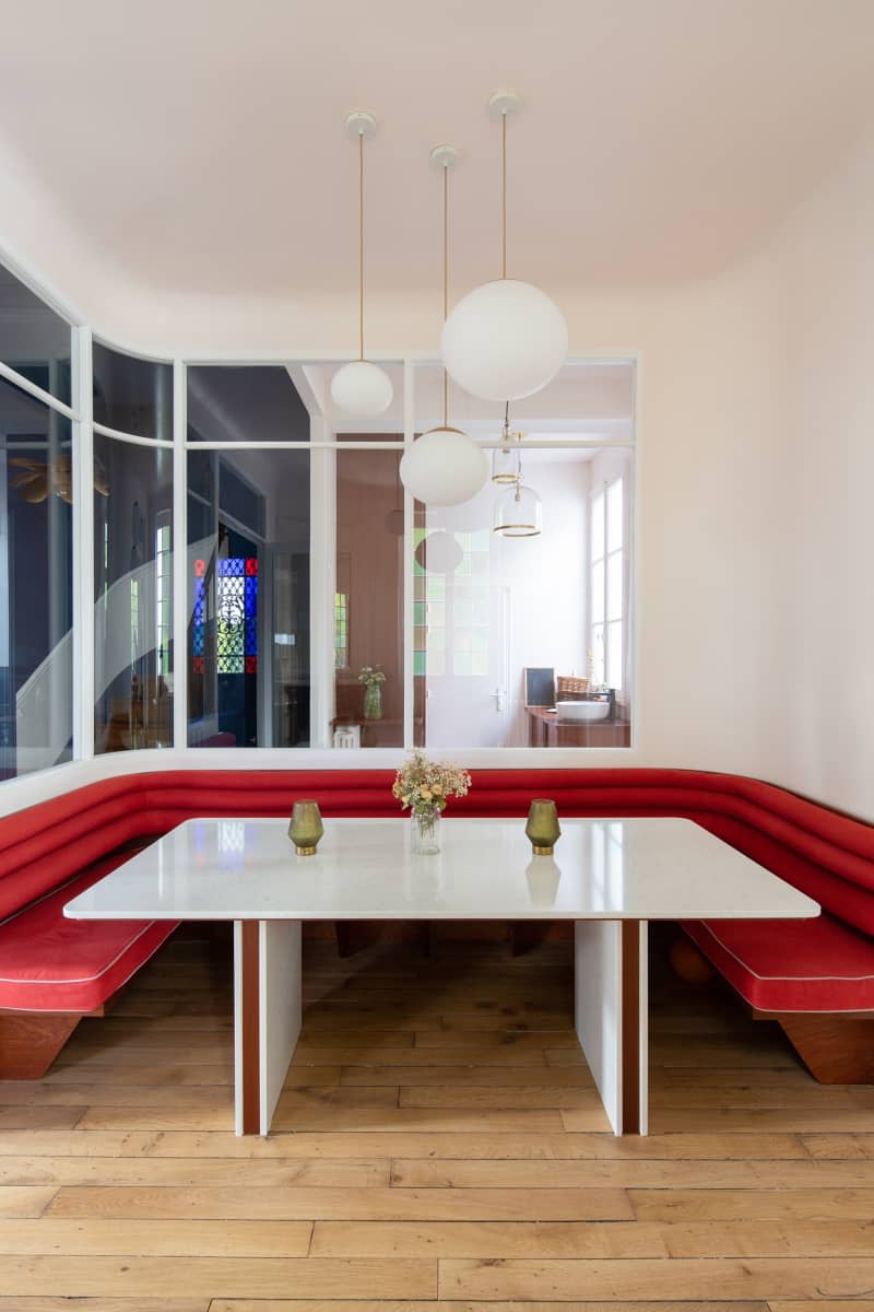 Pendant hanging above dining table in newly renovated dining room with red banquette.