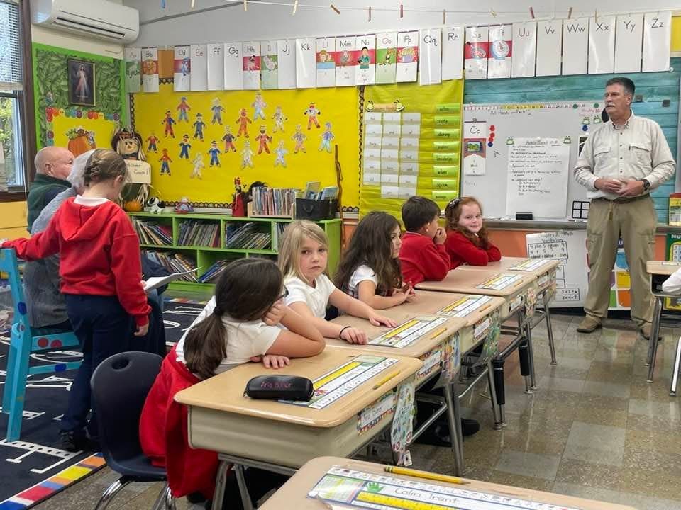 Peter Petrides, right, addressing a first-grade class at St. James School about his military service.