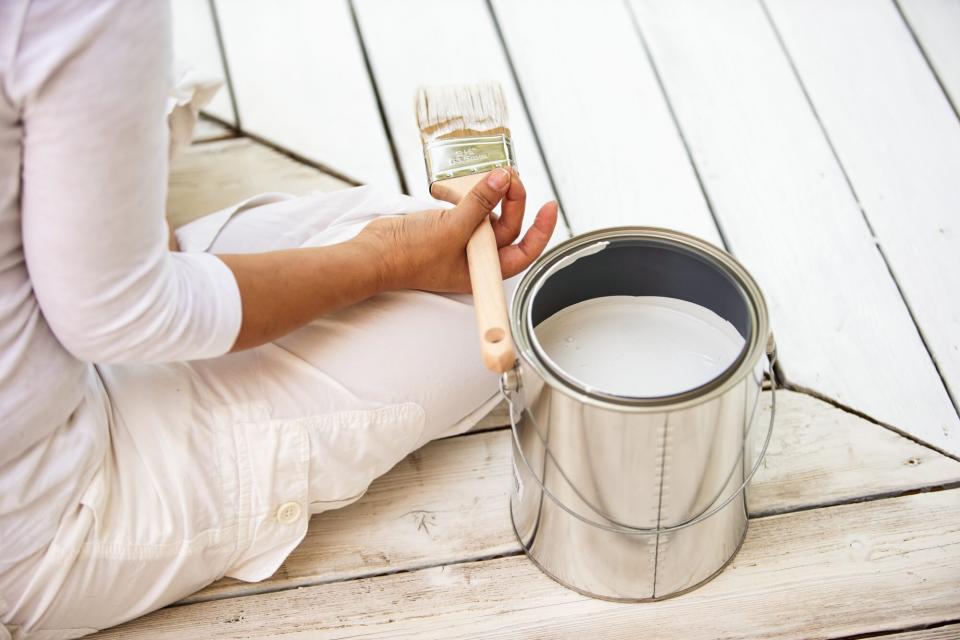 woman holding paint brush, about to paint front porch