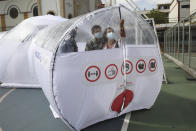 Designers stand inside one of their Portable Epidemiological Insulation Unit during a media presentation, in Bogota, Colombia, Tuesday, Feb. 16, 2021. Colombia’s La Salle University school of architecture designed the small polyhedral pneumatic geodesic domes which can be used to isolate and treat COVID-19 patients in areas where there are no nearby hospitals or where existing hospitals are overwhelmed with patients. (AP Photo/Fernando Vergara)