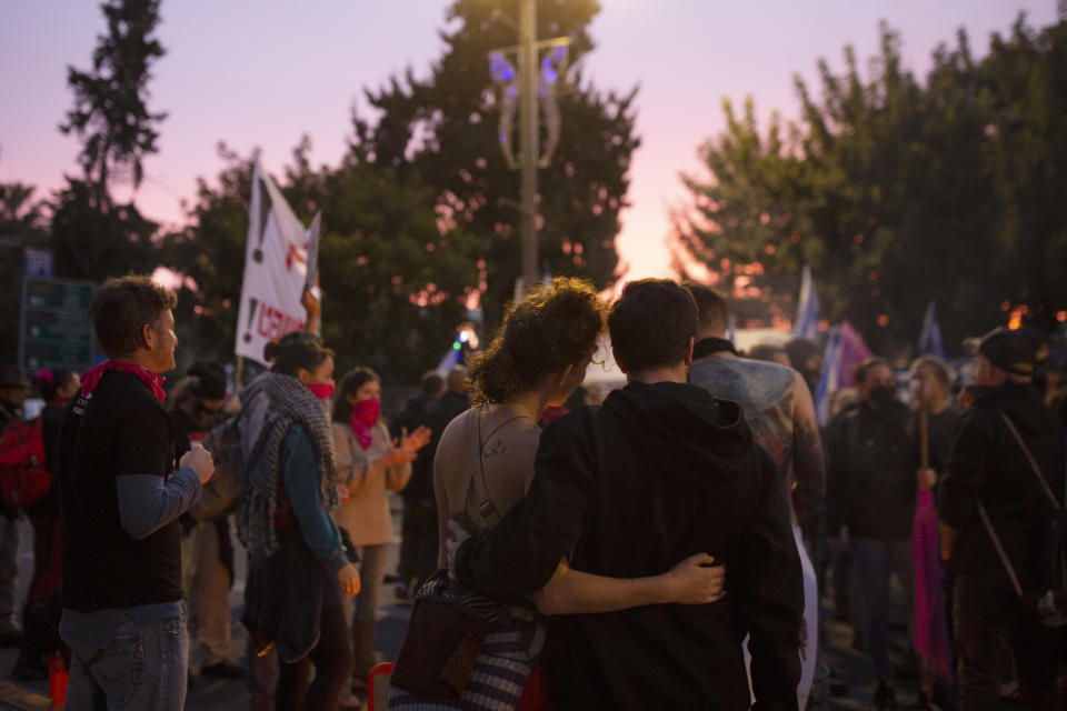 Israeli anti-government protesters hold onto each other as the sun rises outside of the official residence of Prime Minister Benjamin Netanyahu on the day his corruption trial was originally scheduled before it was postponed, in Jerusalem, Wednesday, Jan. 13, 2021. (AP Photo/Maya Alleruzzo)