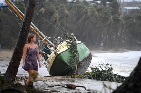 A local resident walks past a yacht that was washed ashore after Cyclone Debbie hit the northern Queensland town of Airlie Beach, located south of Townsville in Australia, March 29, 2017. AAP/Dan Peled/via REUTERS