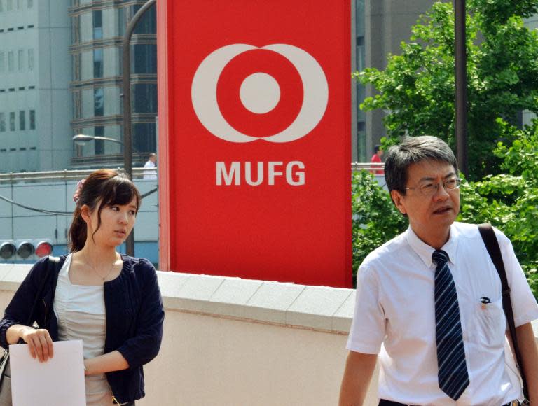 People pass a signboard for Japan's Bank of Tokyo-Mitsubishi UFJ in Tokyo on May 17, 2013