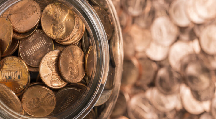 Pennies in a jar on top of a background of blurred pennies. Penny stocks.