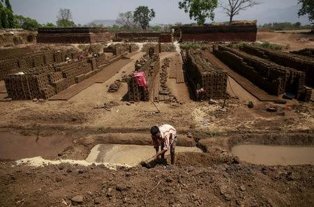 A labourer prepares a mixture for making mud bricks at a kiln in Karjat, India, March 10, 2016. REUTERS/Danish Siddiqui