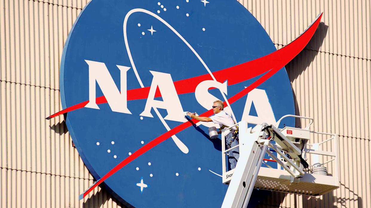  A worker performing maintenance at an exterior NASA logo. 