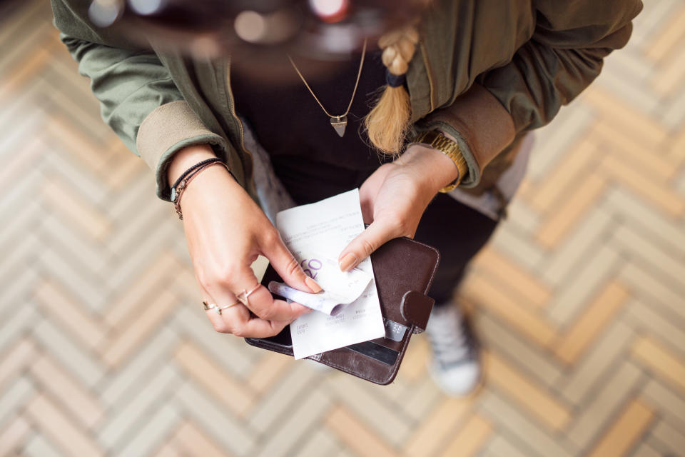 A person looking at a note from a wallet