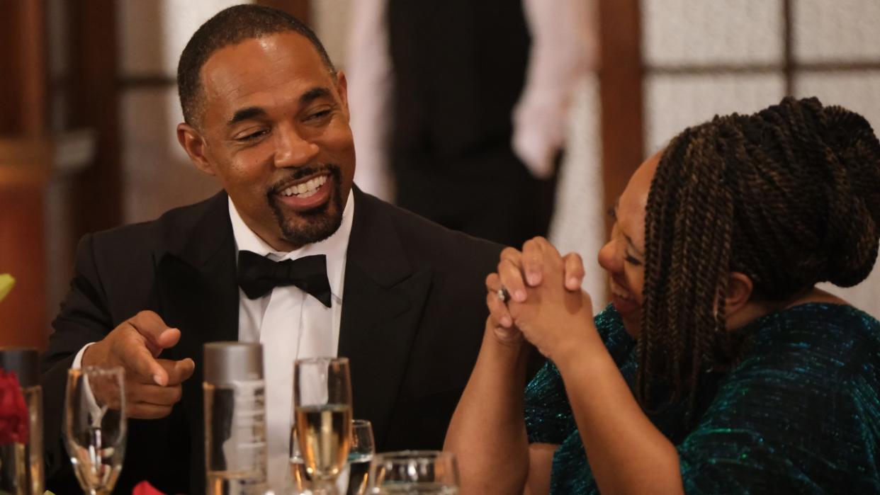  Jason George as Ben Warren laughs with Chandra Wilson as Miranda Bailey as they sit at a table during a firefighters banquet on the May 18, 2024, episode of Station 19, "Glamorous Life.". 